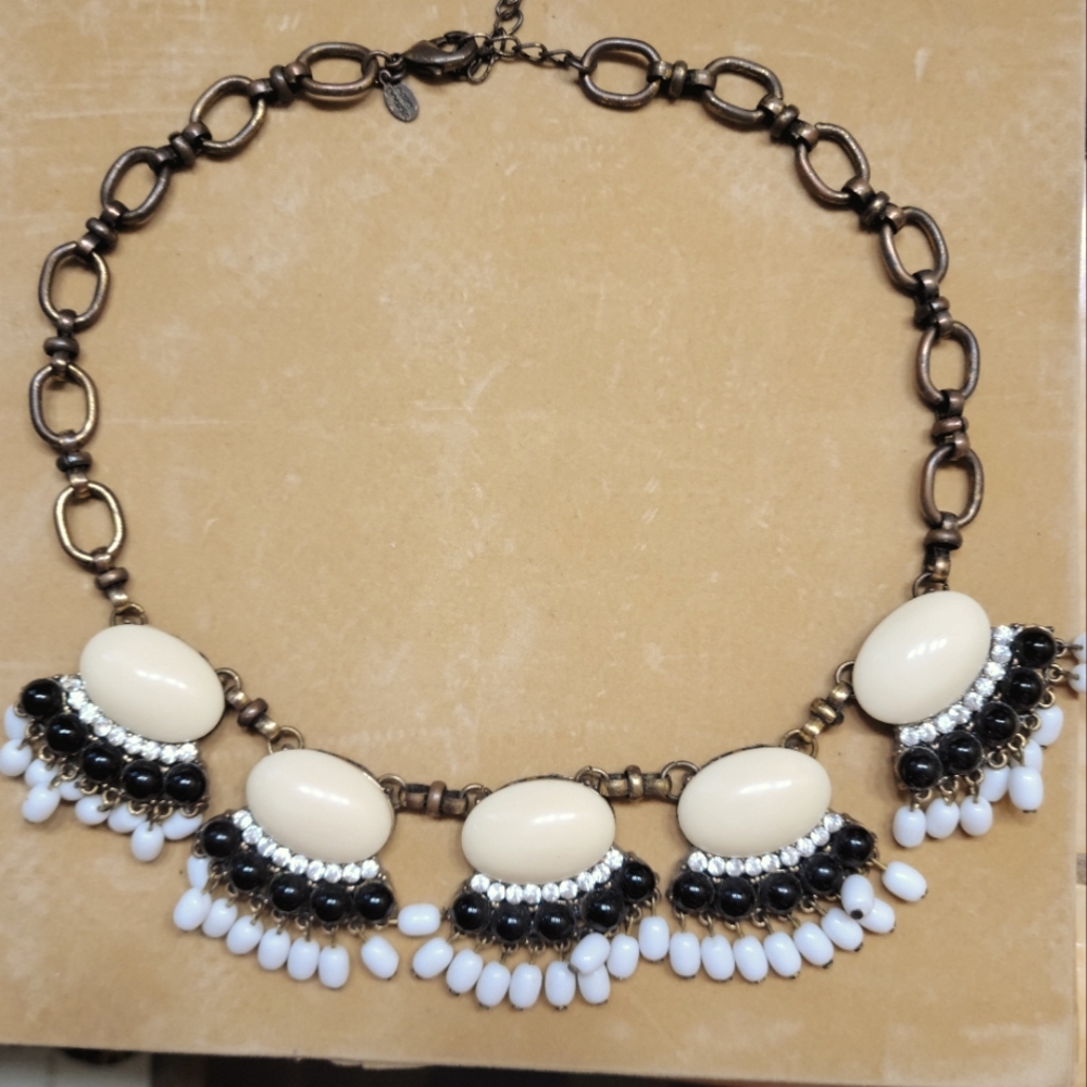 Burnished gold-metal color bib-style necklace.   Cream, black, white beads